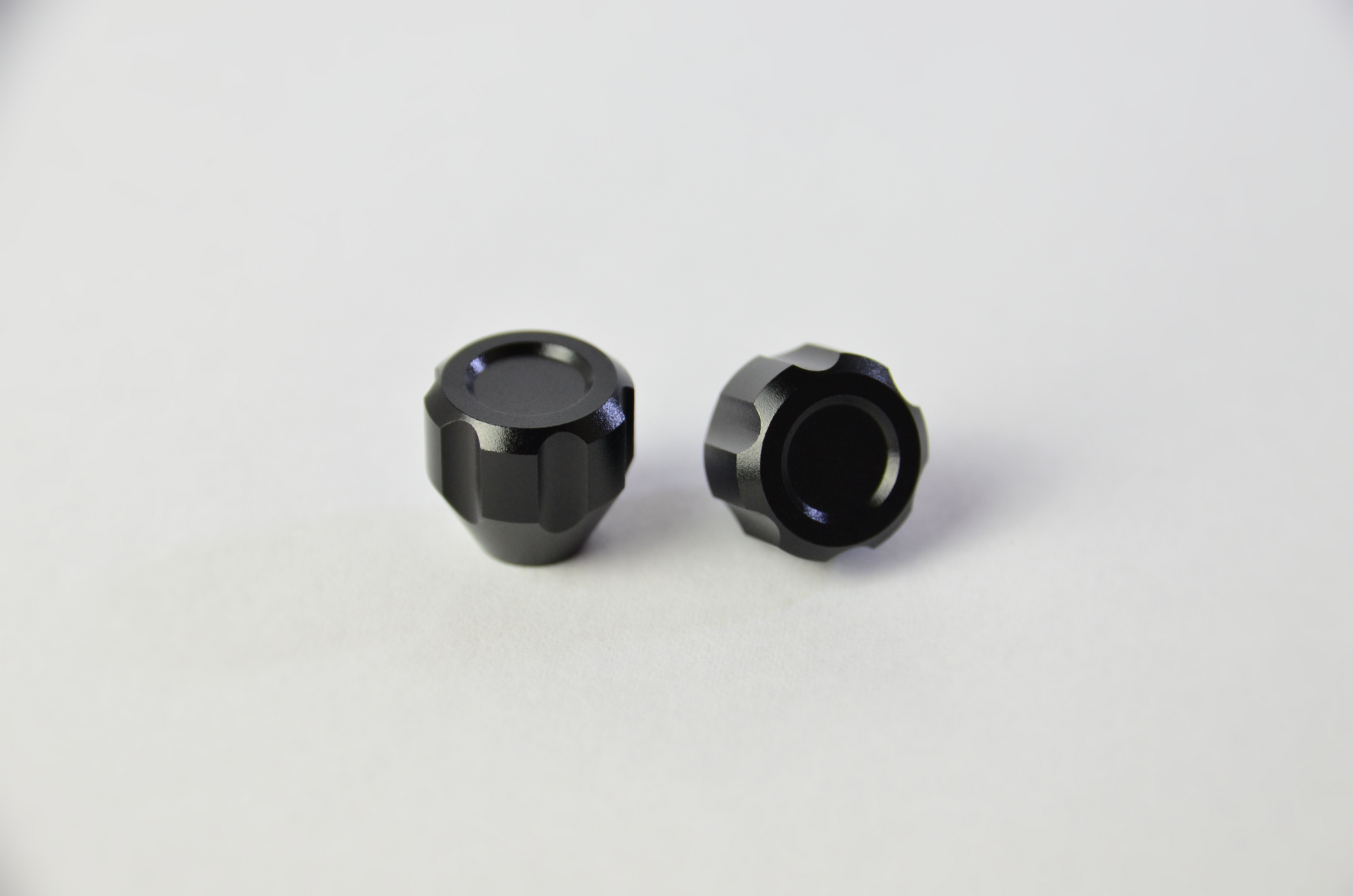 Two black anodized aluminium switch knobs for sim racing DIY projects. Front side view.