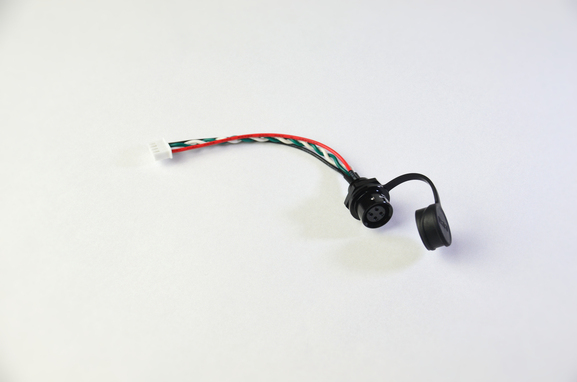 A Weipu to JST connector cable with black, red, white and green wires, a white connector on one end and a black Weipu connector on the other.